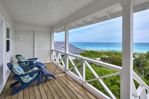 a porch with a blue rocking chair and the ocean at Bohemia Bungalow - Two home in James Cistern
