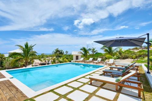 a swimming pool with lounge chairs and an umbrella at Bohemia Two Bedroom home in James Cistern