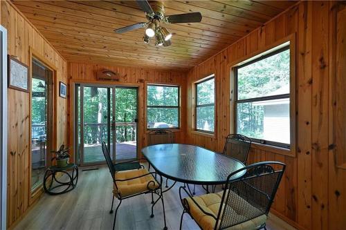 a dining room with a table and chairs and windows at Spooner Shores - Wooded, Lakefront Retreat in Spooner