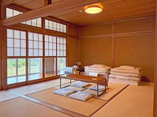 sala de estar con mesa y algunas almohadas en 広い縁側とタタミの部屋に天井吹抜けのオープンキッチンがある一軒家でキッチンやバスルームは最新設備, en Komoro