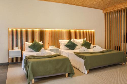 a bedroom with two beds with green and white pillows at Fonte da Rosa Guest House Central Studio in Belmonte