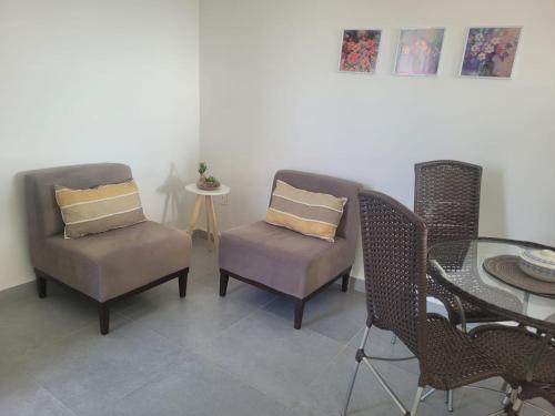 un salon avec deux chaises et une table dans l'établissement Ap em Juazeiro do Norte com dois quartos com cama de casal e ar condicionado, à Juazeiro do Norte