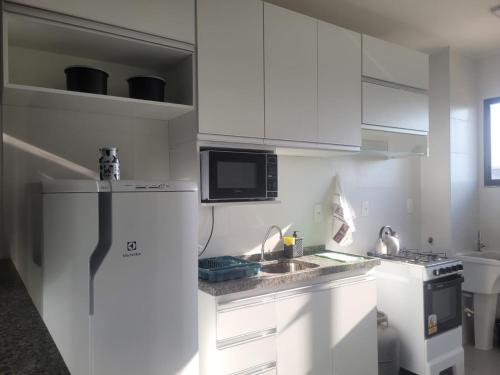 une cuisine avec des armoires blanches et un réfrigérateur dans l'établissement Ap em Juazeiro do Norte com dois quartos com cama de casal e ar condicionado, à Juazeiro do Norte