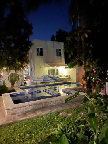 a swimming pool in front of a house at night at Villa Escondida Guest House Cozumel Downtown in Cozumel