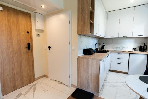 a small kitchen with white cabinets and a door at Rajska7712 in Wrocław