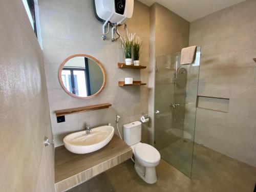 Un baño con lavabo, inodoro y espejo. en Badung Villa no 4, en Ungasan