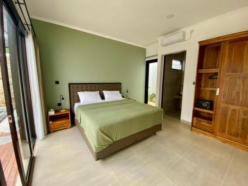 Un dormitorio con una cama con una pared verde. en Badung Villa no 4, en Ungasan