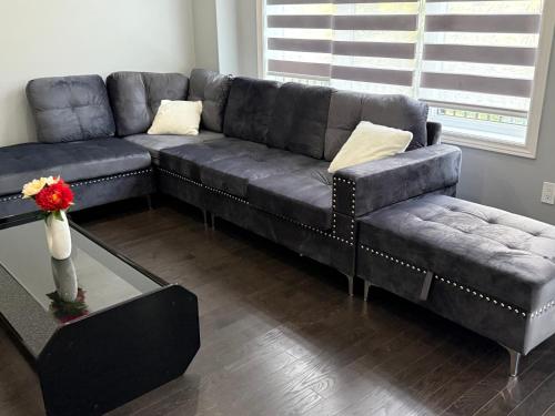 a living room with a black couch and a table at Comfy Basement Suite in Quiet Neighbourhood in Whitby