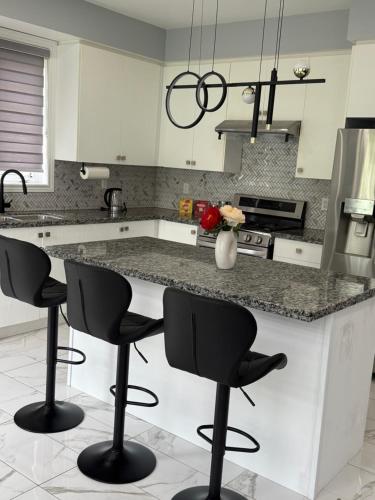 a kitchen with a counter with four bar stools at Comfy Basement Suite in Quiet Neighbourhood in Whitby
