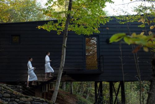 two people walking on a bridge in front of a house at Lopota Lake Resort & Spa in Napareuli