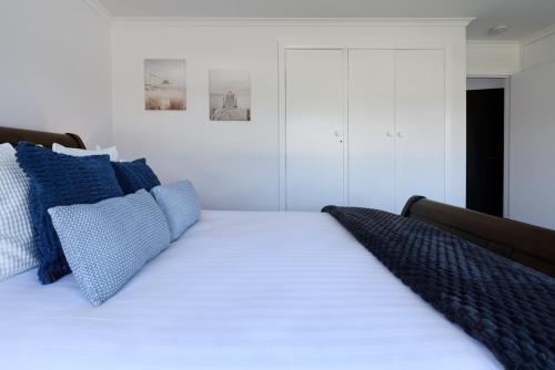 a white bed with blue pillows on top of it at Modern Ease in East Devonport in Devonport