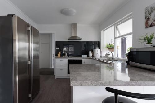 a large kitchen with a stainless steel refrigerator at Modern Ease in East Devonport in Devonport