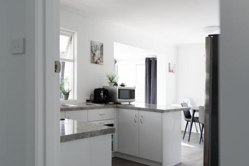 a kitchen with white cabinets and a microwave at Modern Ease in East Devonport in Devonport