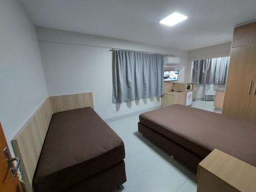 a small bedroom with a bed and a television at Acqua Ville 2 - Apartamentos JN in Caldas Novas