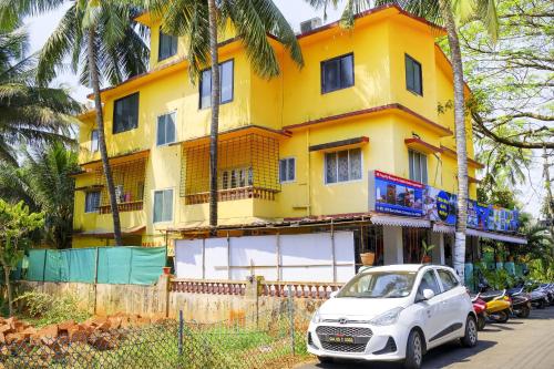 a white car parked in front of a yellow building at Hotel O Mahamaya Holiday Inn in Goa