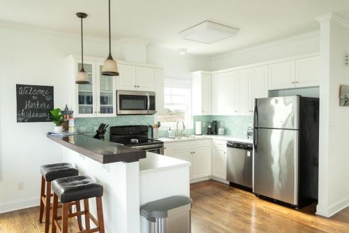a kitchen with white cabinets and a stainless steel refrigerator at Harkers Hideaway - Waterfront with Private Beach in Harkers Island