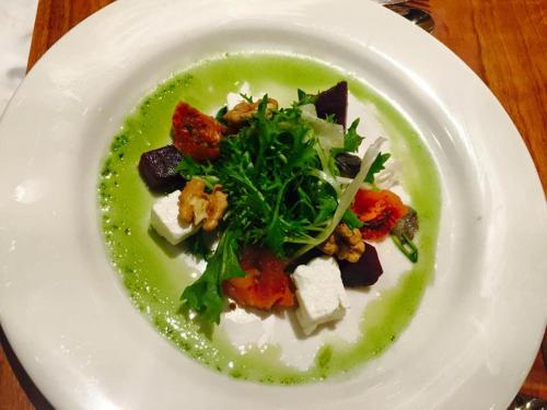 a white plate with a green dish with food on it at Villa Bella Boutique Hotel in Kavadarci