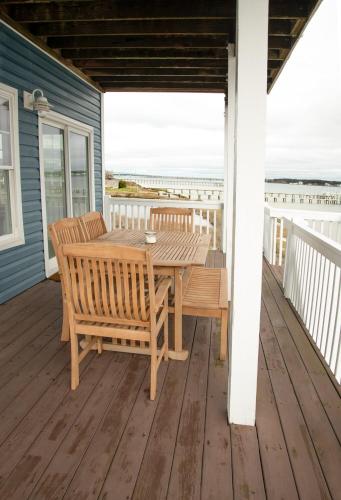 a wooden table and chairs on a deck with the beach at Harkers Hideaway - Waterfront with Private Beach in Harkers Island