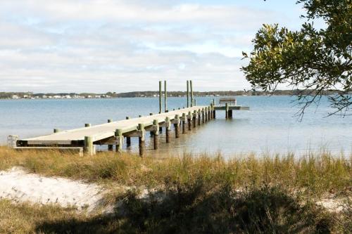 a dock on a lake with a bird sitting on it at Harkers Hideaway - Waterfront with Private Beach in Harkers Island