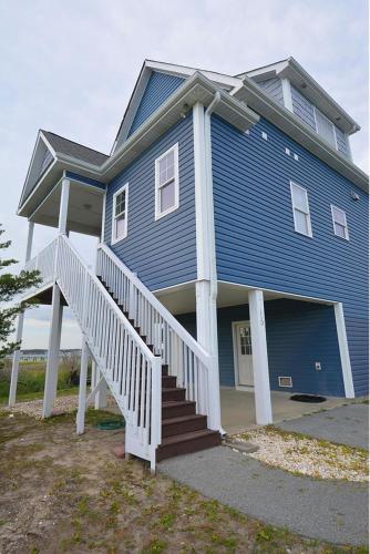a large blue house with a white porch and stairs at Harkers Hideaway - Waterfront with Private Beach in Harkers Island