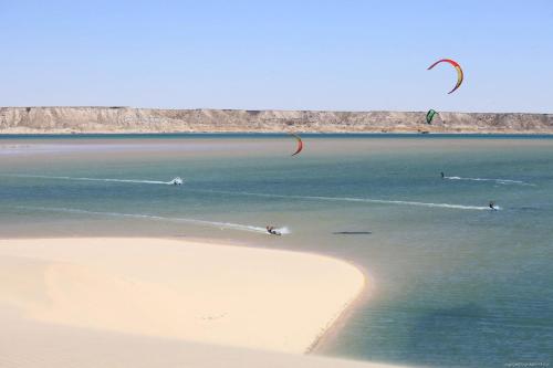 a group of people flying kites on a beach at Dar Rio Oro in Dakhla