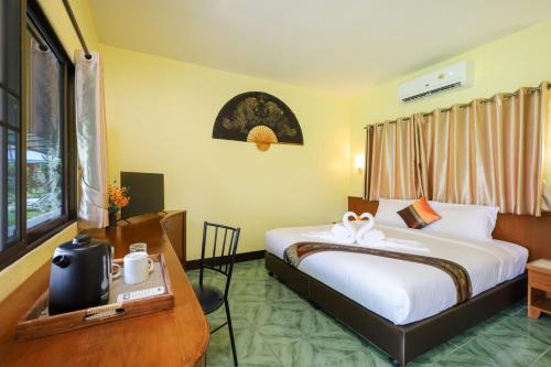 a hotel room with a bed and a table and a desk at The Golddiggers Resort in Nai Yang Beach