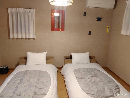 Zimmer mit 2 Betten in einem Zimmer mit Kronleuchter in der Unterkunft ファミーユグループ城ケ崎店 海音Umine in Ito