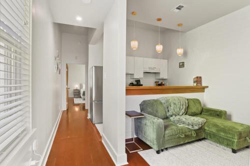 Una sala de estar con un sofá verde y una cocina. en Perfectly Located 1 Bedroom I Uptown - Magazine St, en Nueva Orleans