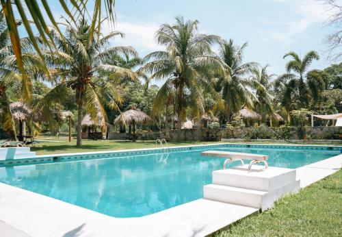 una piscina con palmeras al fondo en Cabaña 0, en Coyote