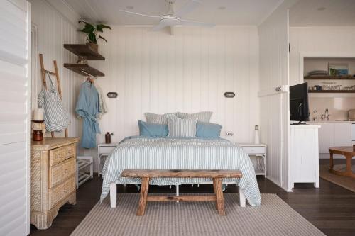 a bedroom with a bed with a bench in it at Bay Properties The Beach House in Yamba