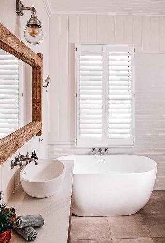 a white bathroom with a tub and a sink at Bay Properties The Beach House in Yamba
