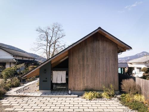 a small wooden house with a brick driveway at COCO VILLA 湯布院-Yufuin- in Yufu