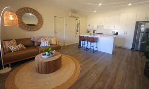 a living room with a couch and a table and a kitchen at Piper Apartment in Bathurst