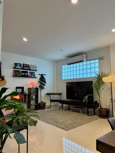 a living room with a flat screen tv and plants at Baan Farang in Bangkok