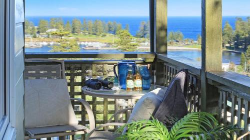 a table and chairs on a balcony with a view of the ocean at Flipside Apartment in Kiama