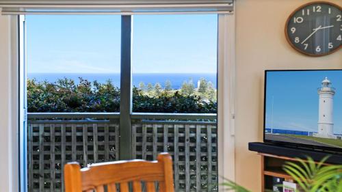 a clock and a window with a view of a lighthouse at Flipside in Kiama