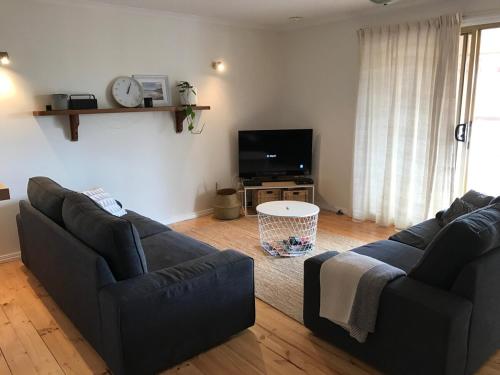 a living room with two couches and a flat screen tv at Southside at Vivonne in Vivonne Bay