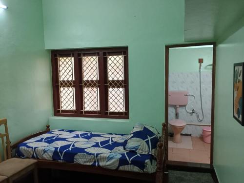 a bedroom with a bed and a window and a bathroom at Home away from home in Palakkad in Palakkad