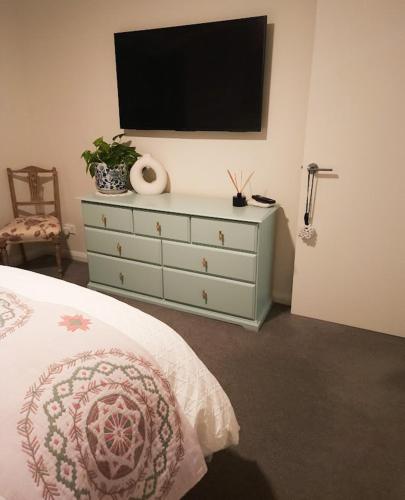 a bedroom with a dresser with a television on the wall at Piper Apartment in Bathurst