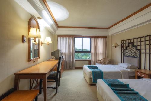 Una habitación de hotel con dos camas y un escritorio con una computadora. en Hotel Sahid Bandar Lampung, en Bandar Lampung
