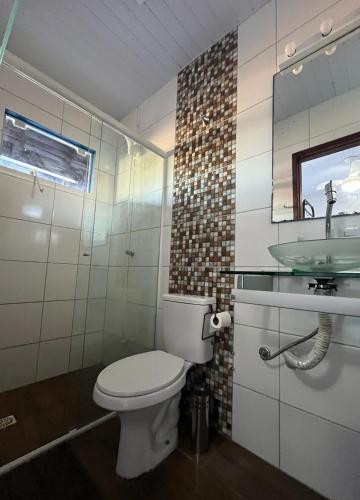 a bathroom with a toilet and a sink at Inn Nature Pousada Casa de Veraneio com piscina in Palhoça