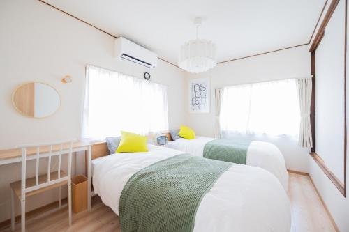 Dos camas en una habitación con paredes y ventanas blancas. en Happiness Ohama一軒家東名静岡インター五分, en Shizuoka