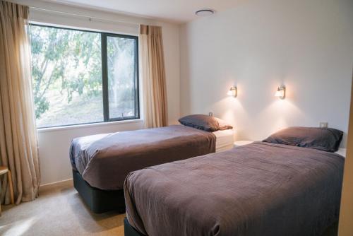 two beds in a hotel room with a window at Cardrona Alpine Villa by Sothebys Luxury Rental Homes in Cardrona