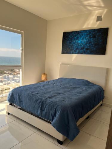a bedroom with a blue bed and a large window at Rosarito Sol y Mar Getaway in Rosarito Beach