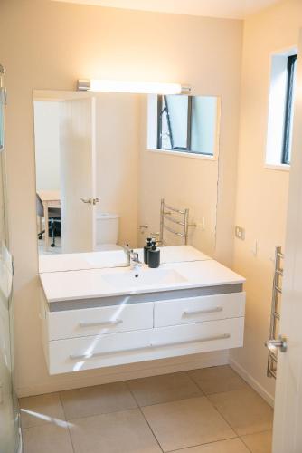 a bathroom with a white sink and a mirror at Cardrona Alpine Villa by Sothebys Luxury Rental Homes in Cardrona