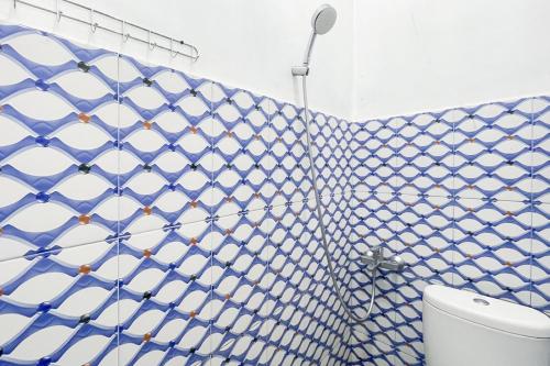 baño de azulejos azules y blancos con aseo en RedDoorz near Simpang Panei Medan, en Pematangsiantar