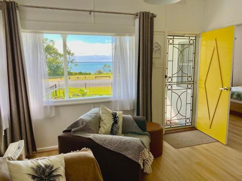 a living room with a couch and a large window at Osprey - Pet Friendly Waterfront in Callala Bay