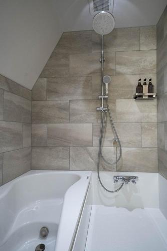 a bathroom with a white tub and a shower at ERUSA Rusutsu in Rusutsu