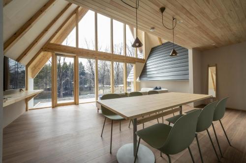 a dining room with a wooden table and green chairs at ERUSA Rusutsu in Rusutsu