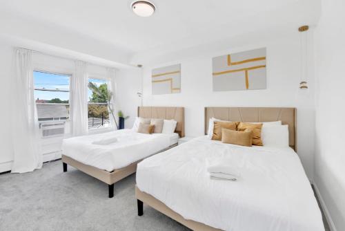 two beds in a white room with a window at Luxury 5 BR 2BA Apt NYC Sleeps 16 with Free Parking! in Yonkers